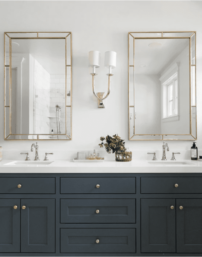 navy blue bathroom vanity with white countertops and mixed metal accents