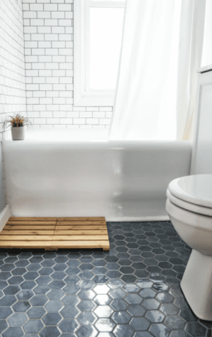 small bathroom with white subway tile around white bathtub and blue hexagon floor tile