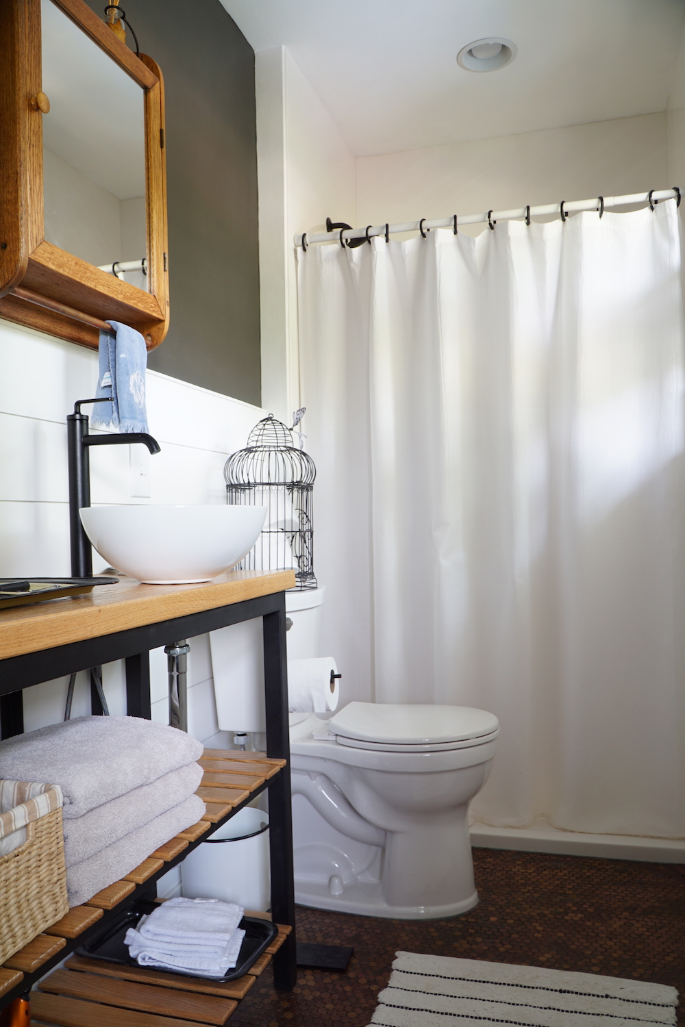 Small bathroom with white shiplap walls, modern industrial vanity and white shower curtain.