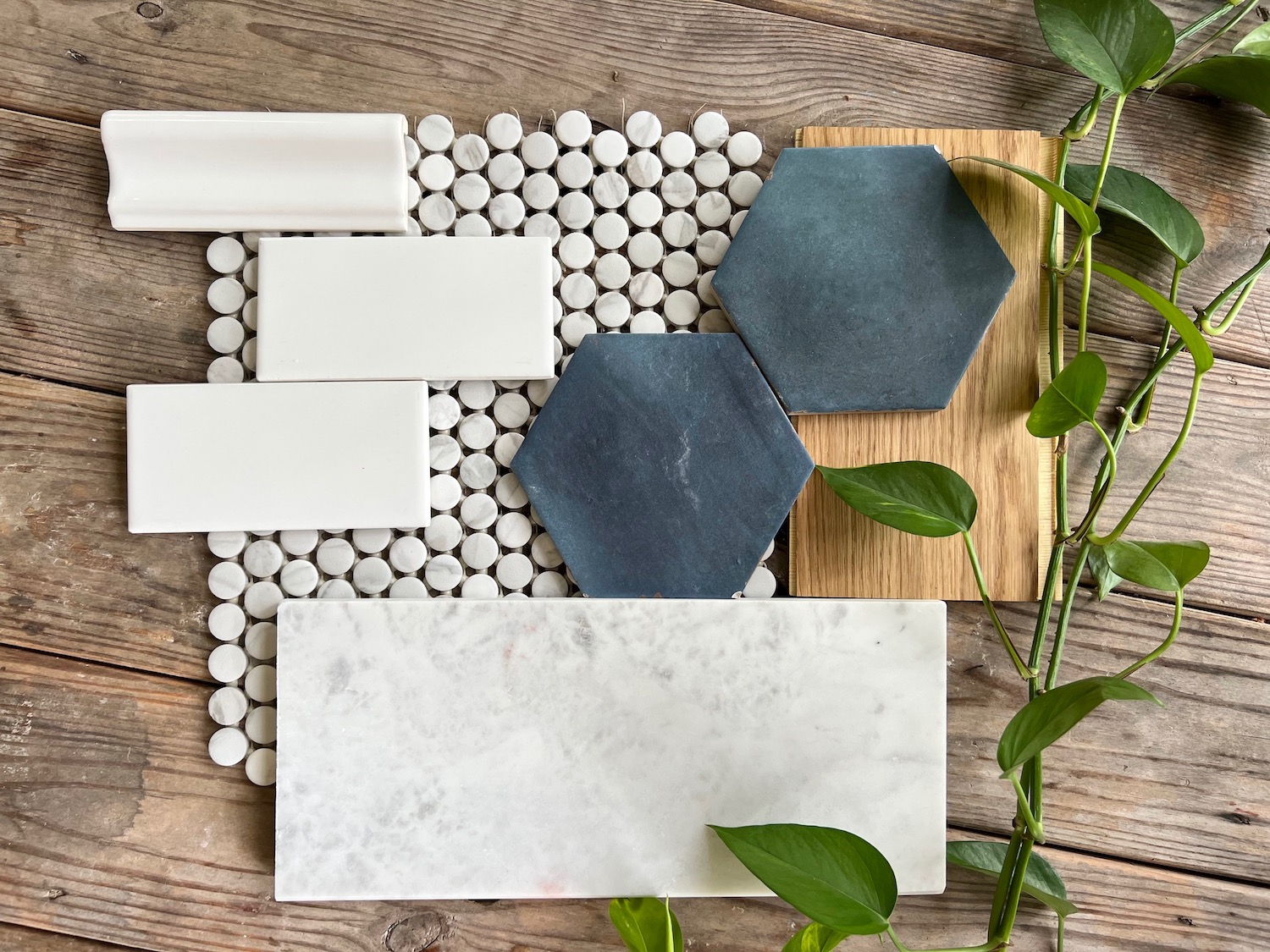 flay lay of several tile samples - white subway tile, chair rail tile, blue hexagonal tile, marble penny tile, and marble stone